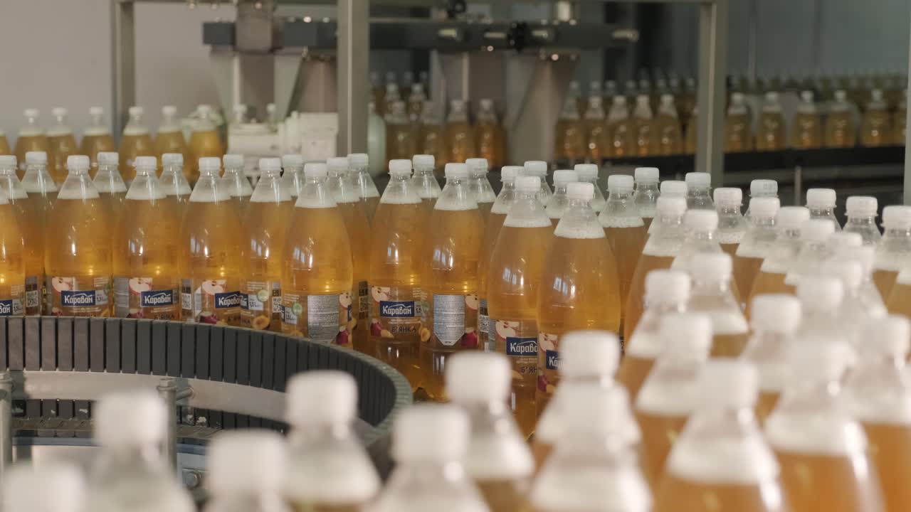Esteira transportadora com garrafas para suco ou água em uma moderna fábrica de bebidas. Produção moderna de água gaseificada doce.