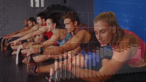 Group performing seated forward stretches on gym floor, displaying floating fitness charts and data