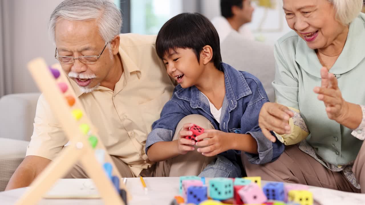 Elderly couple and young boy joyfully play a colorful dice game, fostering intergenerational connection in a warm, well-lit living room