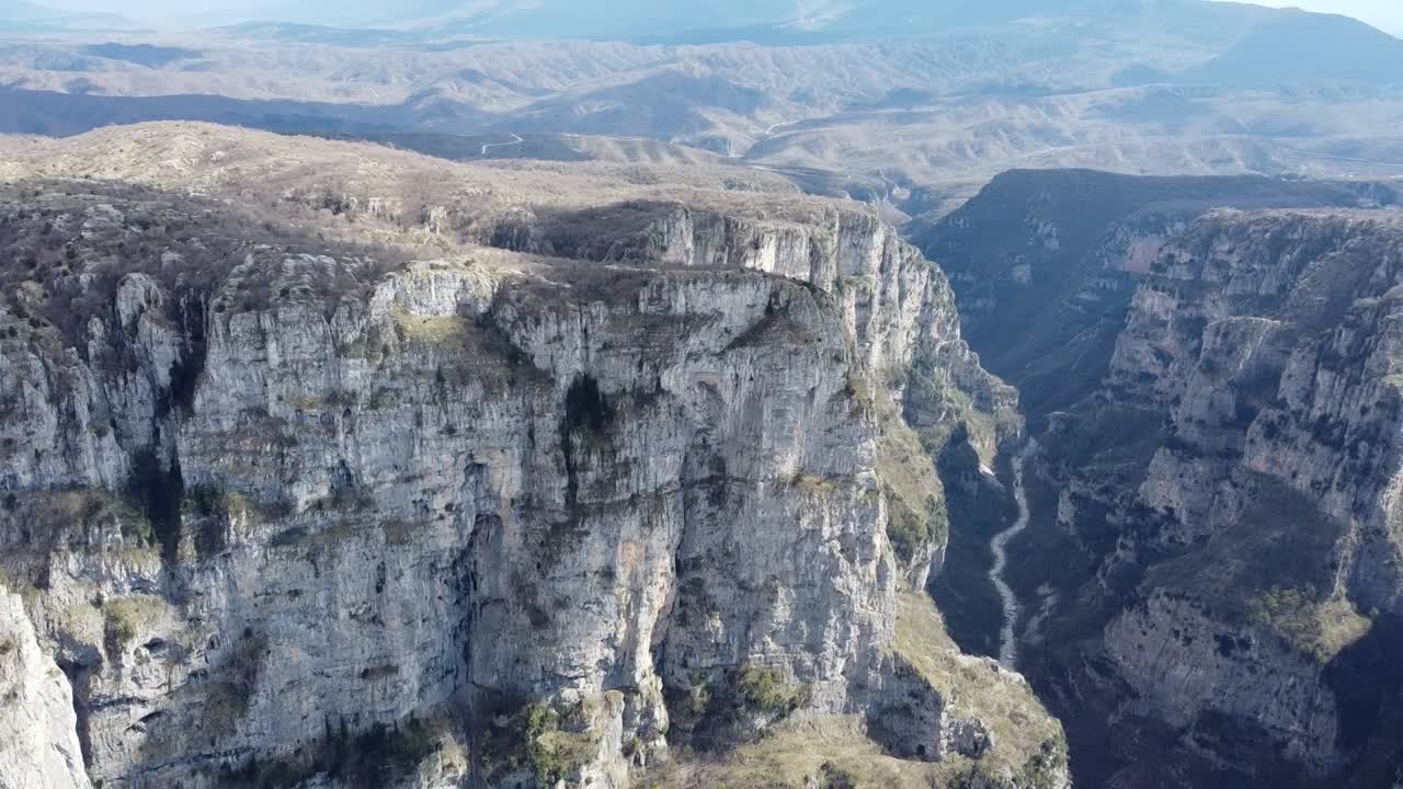 Uma rotação cinematográfica de drone de 360 graus sobre o majestoso Desfiladeiro de Vikos. Capturando uma vista panorâmica completa das imponentes falésias de calcário e da paisagem montanhosa selvagem de Zagori, Epiro.