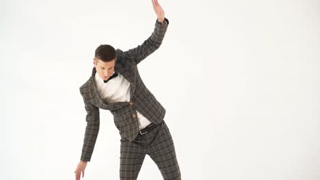 a showman in a plaid suit and white shirt is parodying a businessman with his manners on a white background in the studio