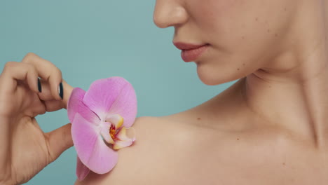 close up beauty portrait beautiful woman touching body with colorful pink orchid flower caressing smooth healthy skin complexion enjoying fresh natural fragrance skincare concept