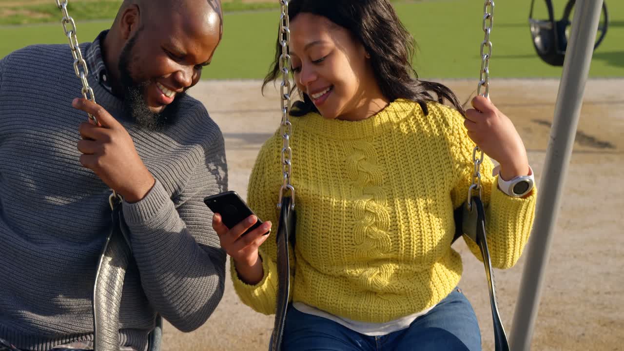 pareja feliz usando el teléfono móvil en el parque en un día soleado 4k