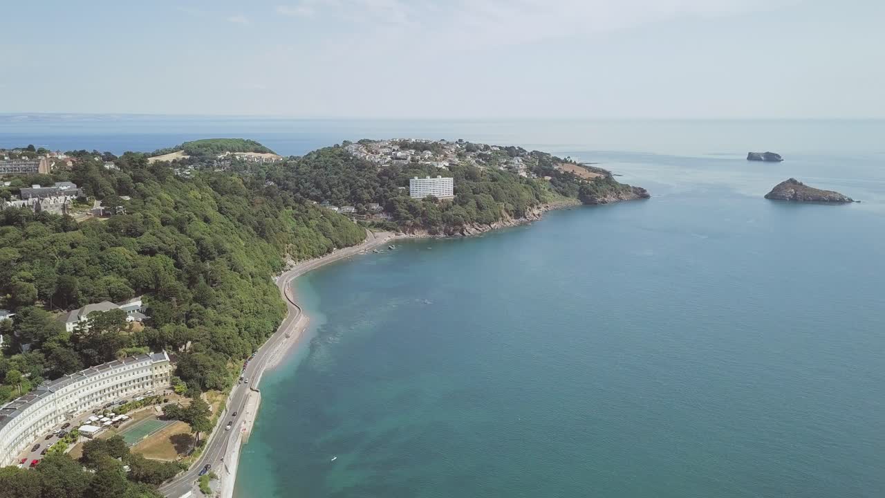 Aerial view of a coastline with buildings, trees, and a road