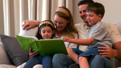 joven familia feliz mirando el álbum de fotos juntos