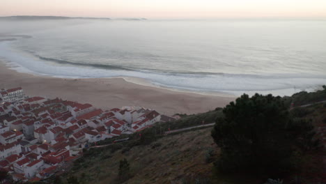 Skyline-And-Beach-Waterfront-Of-Nazaré-Town-In-Portugal---aerial-pullback