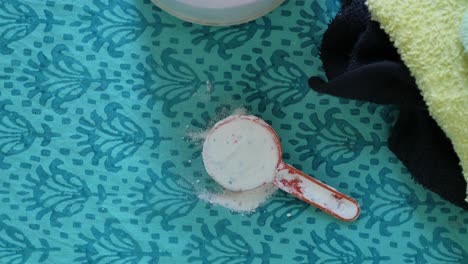 polvo de lavado en cuchara de plástico sobre fondo azul ,