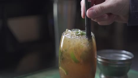 slow motion shot of person putting straw in tasty cynar drink,close up