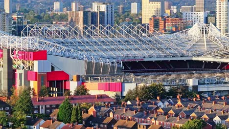 Aerial-zoom-shot-of-famous-Old-Trafford-Stadium-and-neighborhood-in-Manchester-during-golden-sunset