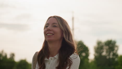 cheerful mom holding hand bag jumping with excitement in park, smiling, hair moving in breeze, casual outfit, joyful motion capturing carefree moment of happy parent enjoying outdoor time