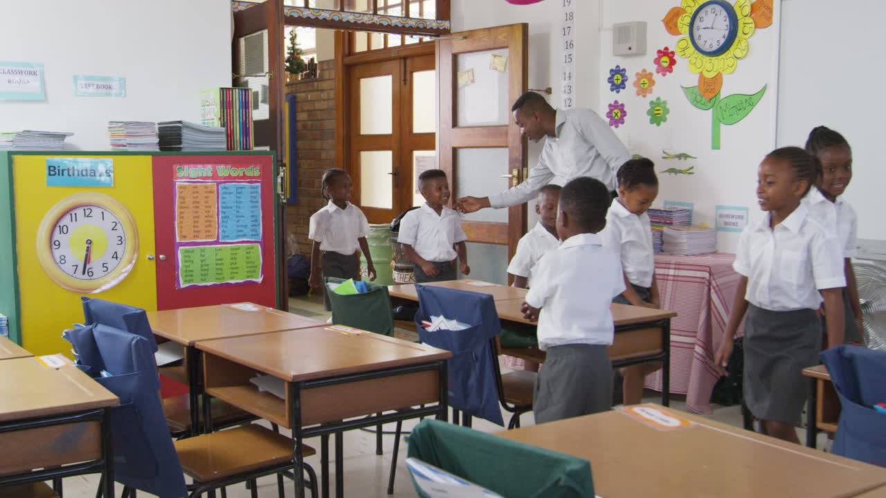 Teacher greets kids arriving at elementary school classroom