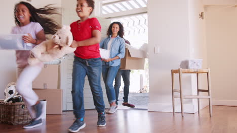 Toma-En-Cámara-Lenta-De-Una-Familia-Emocionada-Llevando-Cajas-A-Su-Nuevo-Hogar-El-Día-De-La-Mudanza