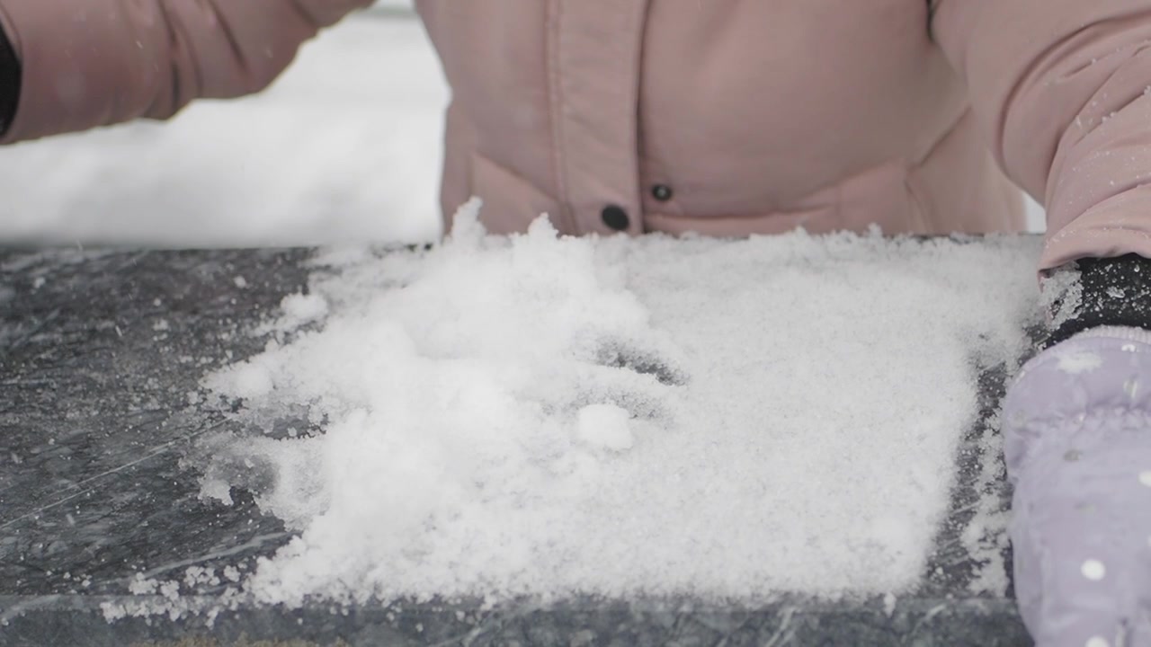 Persona con i Guanti che Forma un Cuore nella Neve Fresca