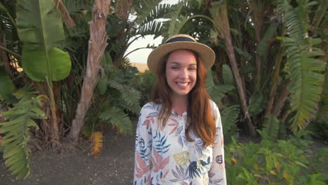 smiling woman in a straw hat posing in palm trees