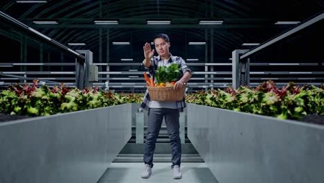 full body of asian male farmer with vegetable basket showing stop sign while standing in smart farm