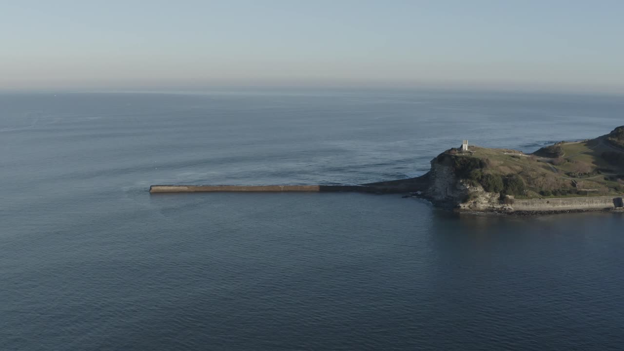 Digue de Sainte-Barbe, seawall, cliff, chapel on headland, Saint-Jean-de-Luz, France. Aerial forward, copy space