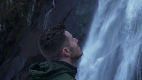 close up man admiring awesome power of natural with flowing waterfall