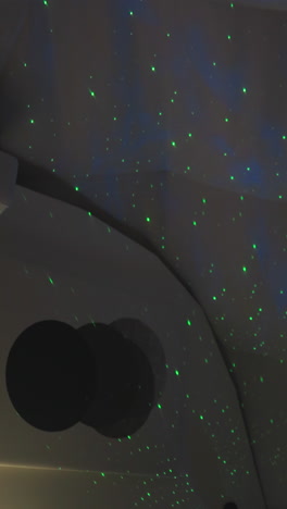 bedroom with projector simulating starry sky. captivating display of green lights on semi-spherical wall of glamping residence. touch of magic to surroundings