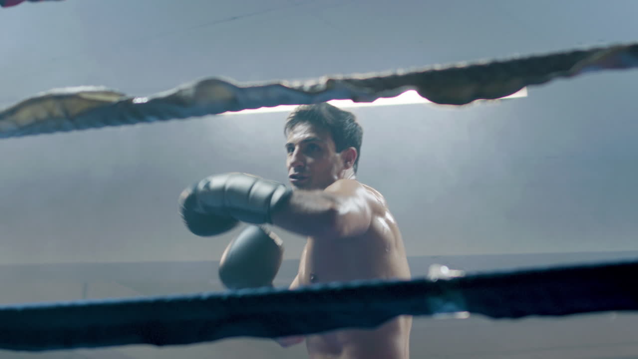 молодой боксер, сражающийся в тени в боксерском зале.