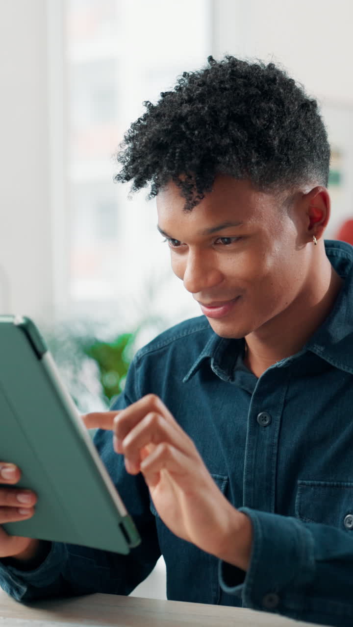 Young Man Smiling While Using a Digital Tablet