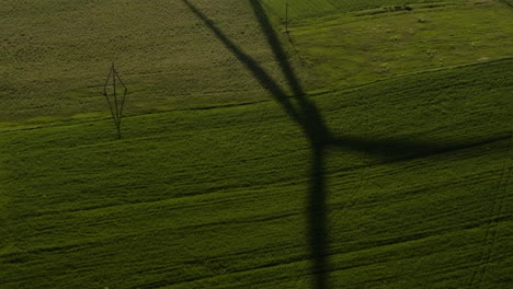 shadow of rotating wind turbine blades on green field in gori, georgia