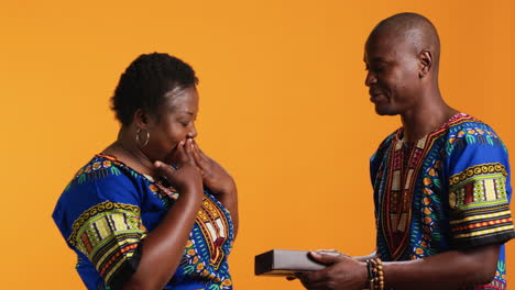 Sweet-husband-giving-giftbox-with-ribbon-to-his-wife