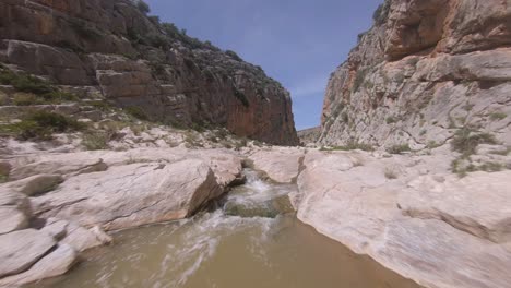 low first person view aerial up shallow river in narrow rock gorge