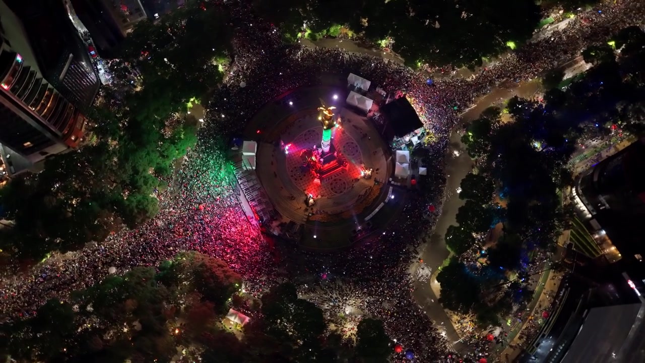 Riprese aeree orbitali del Monumento all'Indipendenza a Città del Messico di notte, pieno di persone che celebrano la vittoria del Messico.