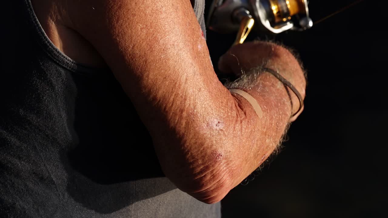 Close-up of an angler's arm reeling in a fishing line, showcasing technique and concentration.