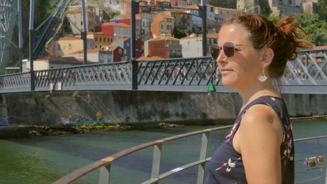 woman taking picture of porto city and river douro with lower deck of dom luis i bridge in the background