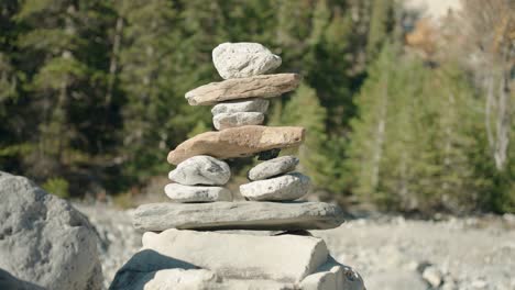 a small man made rock inuksuit statue in a dried up river bed in the bright sun