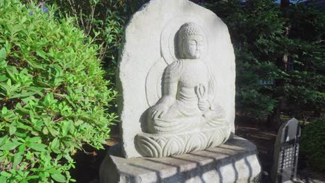 a group of red spider lily next to a buddha statue in a tokyo temple