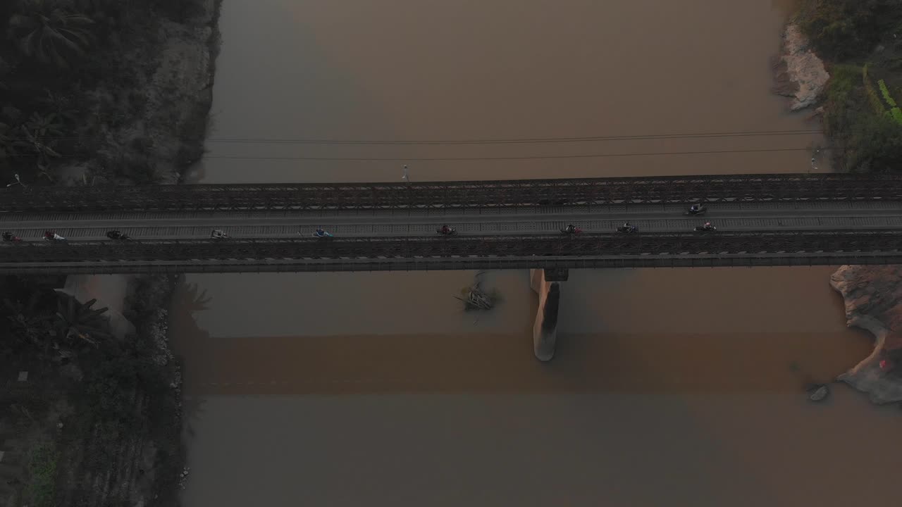 모터사이클이 라오스의 메콩 강을 가로지르는 오래된 다리에서 운전하고 있습니다.