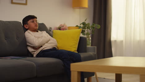 young boy sitting on sofa at home fed up with playing games or streaming onto digital tablet 3