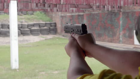 slow motion scenes of the gun firing at a shooting range on the man hand withhold the gun tight and pull the trigger