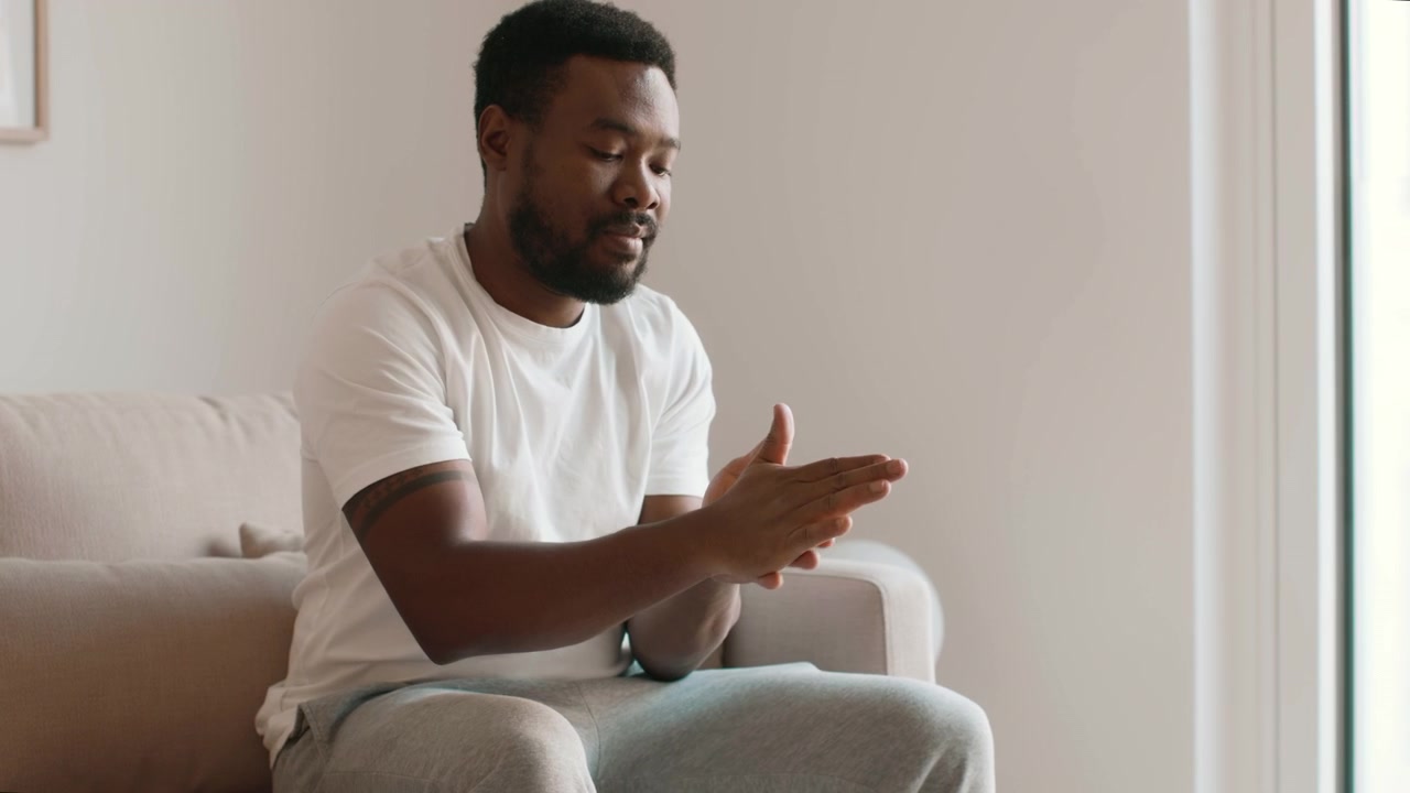 Young Man Applying Hand Sanitizer Spray While Sitting on Sofa