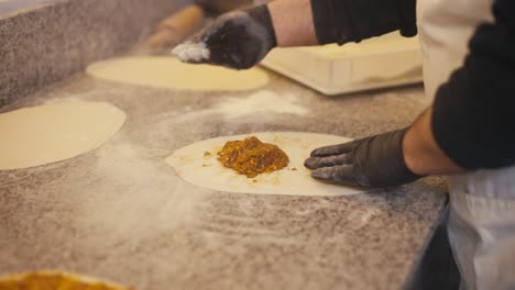 chef preparing kebab filling on dough in a busy kitchen, warm tones and focused task, close-up