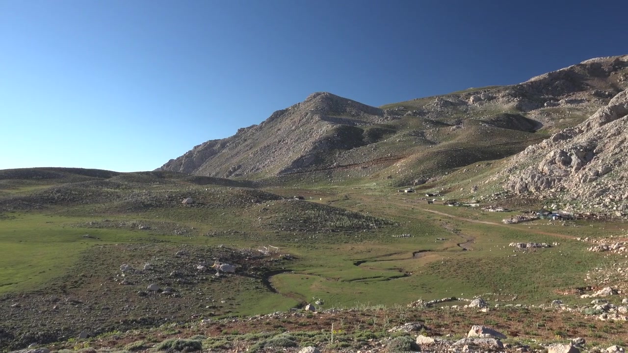 Panoramavy över en klippig bergsdal under en klarblå himmel