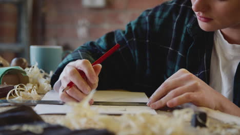 young female carpenter drawing and measuring woodwork design in garage workshop