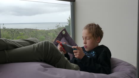 Teenager-boy-playing-on-handheld-game-console