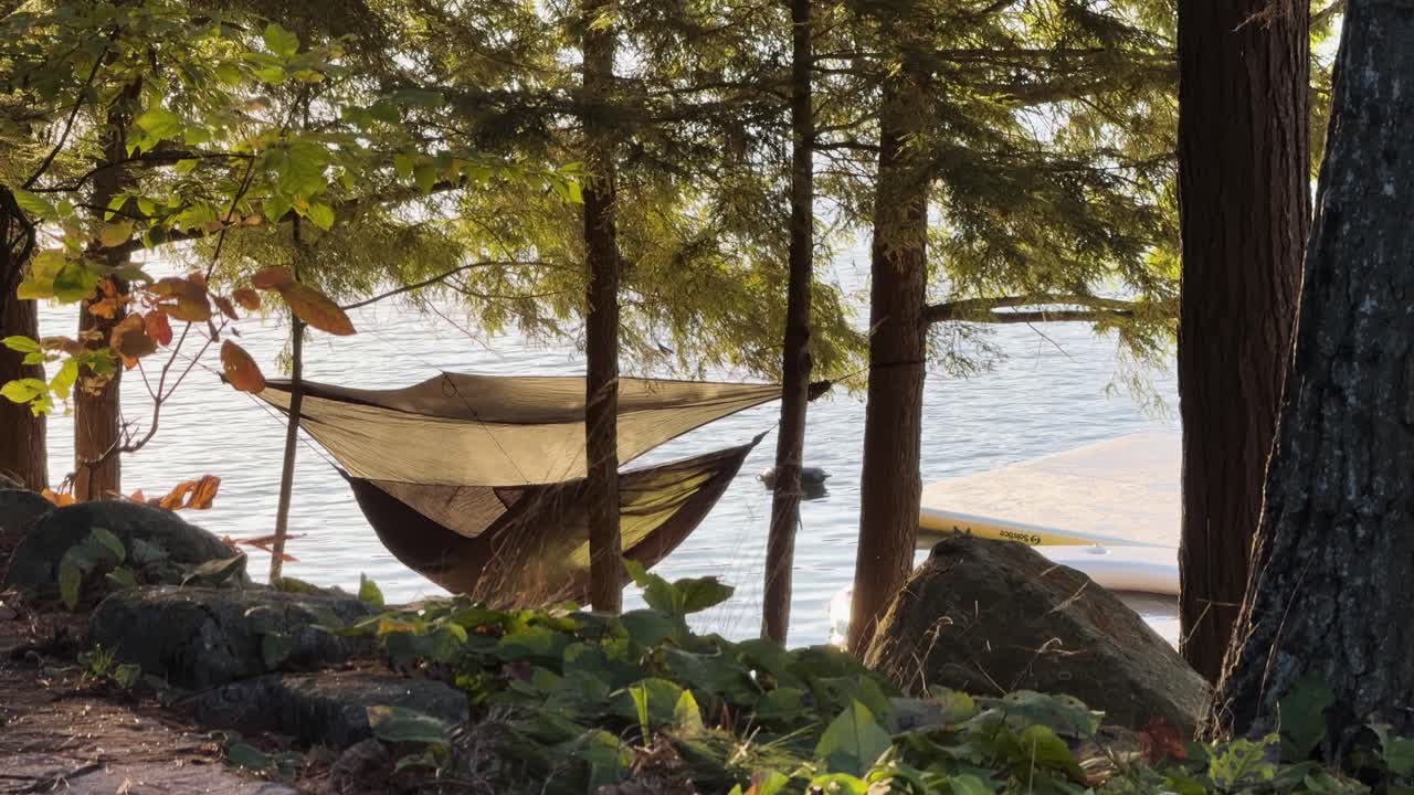 Cozy hammock hanging between trees with lake view in Muskoka Ontario Canada, eco tourism and slow travel wellness