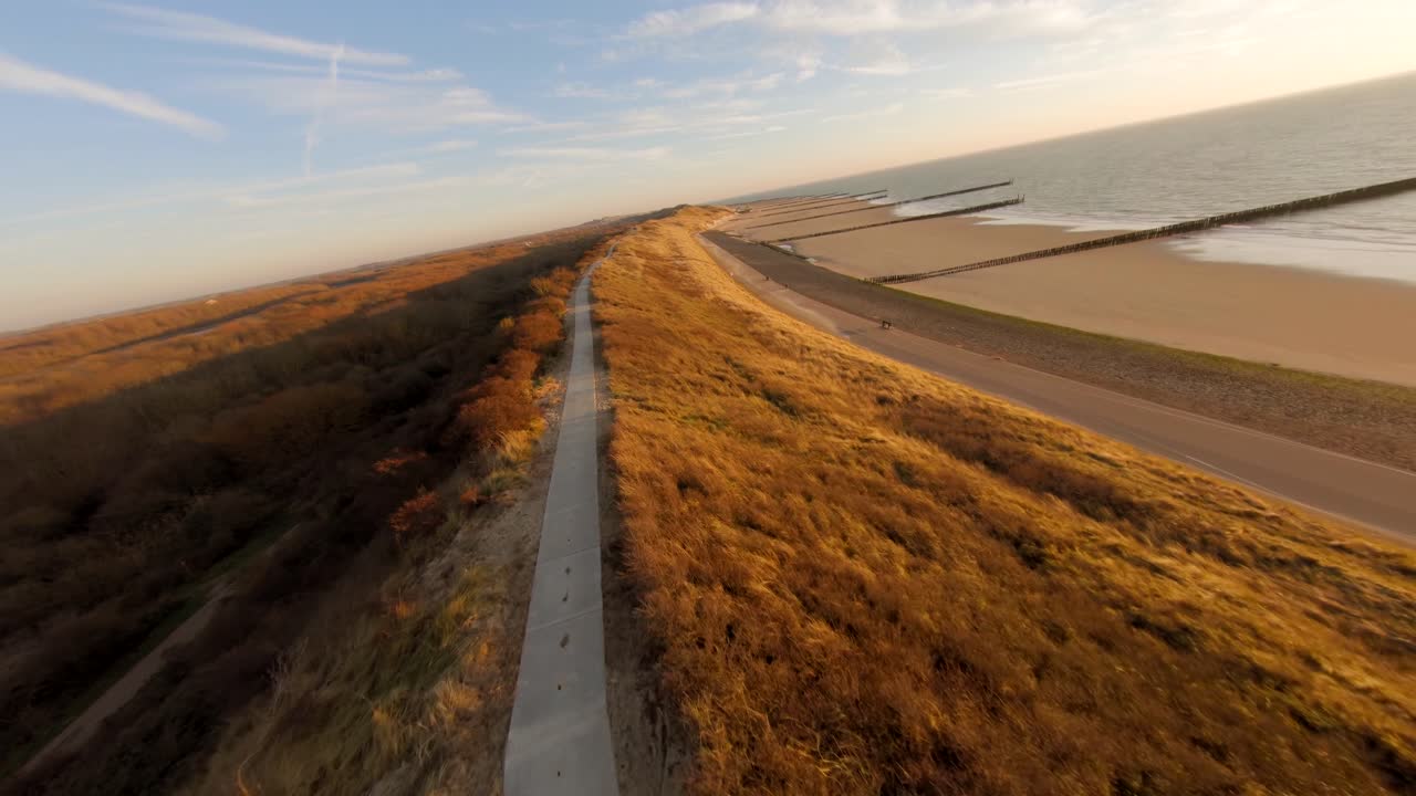 toma aérea rápida de una duna alta con un camino encima durante la hora dorada