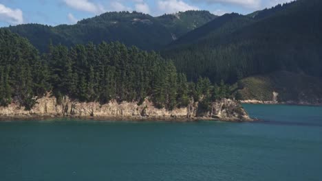forests in the mountains, turquoise bays and coves in the foreground. view from the ferry driving through the malborough sound of new zealand, south island