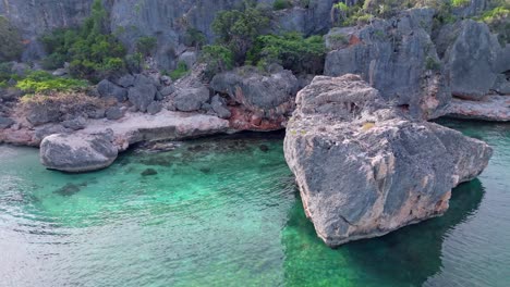 Aerial-sideways,-rocky-coastline-with-large-rocks-in-turquoise-blue-water