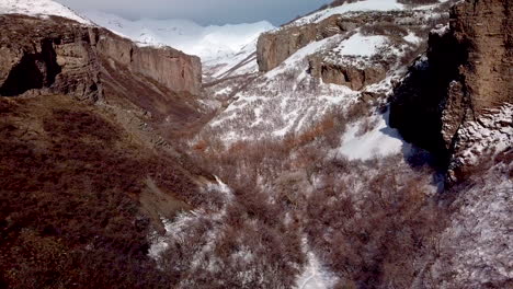 Fliegen-Durch-Eine-Schroffe-Winterliche-Schlucht-Mit-Klippen-Auf-Beiden-Seiten