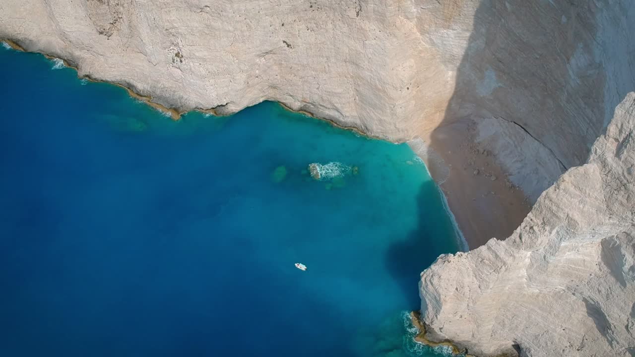 antena girando sobre las aguas azules cristalinas que se mantienen inmóviles a lo largo de los acantilados rocosos de la isla en un día soleado