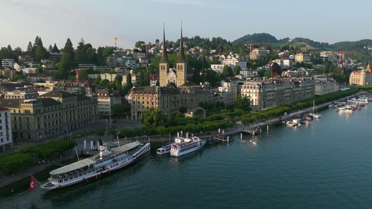 Harborfront scene with boats, dock, and view of historic twin-tower church in background