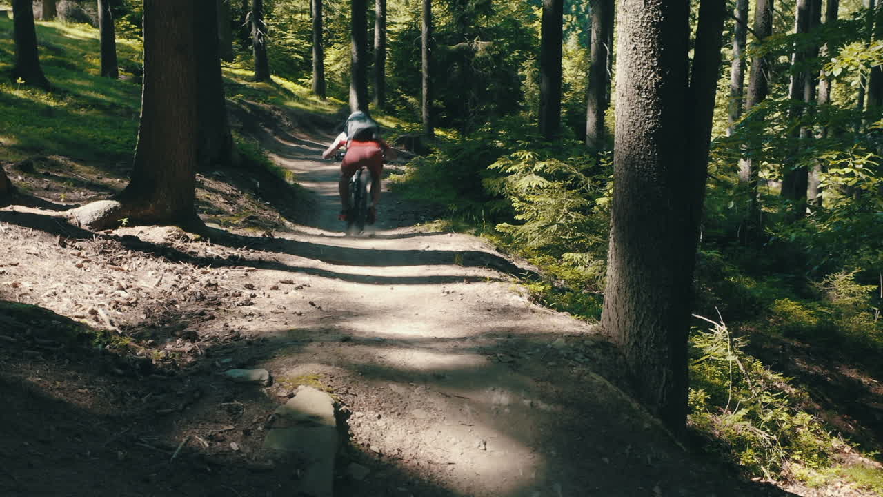 Homme à VTT dévalant rapidement un sentier – plan cinématographique avec caméra en mouvement.