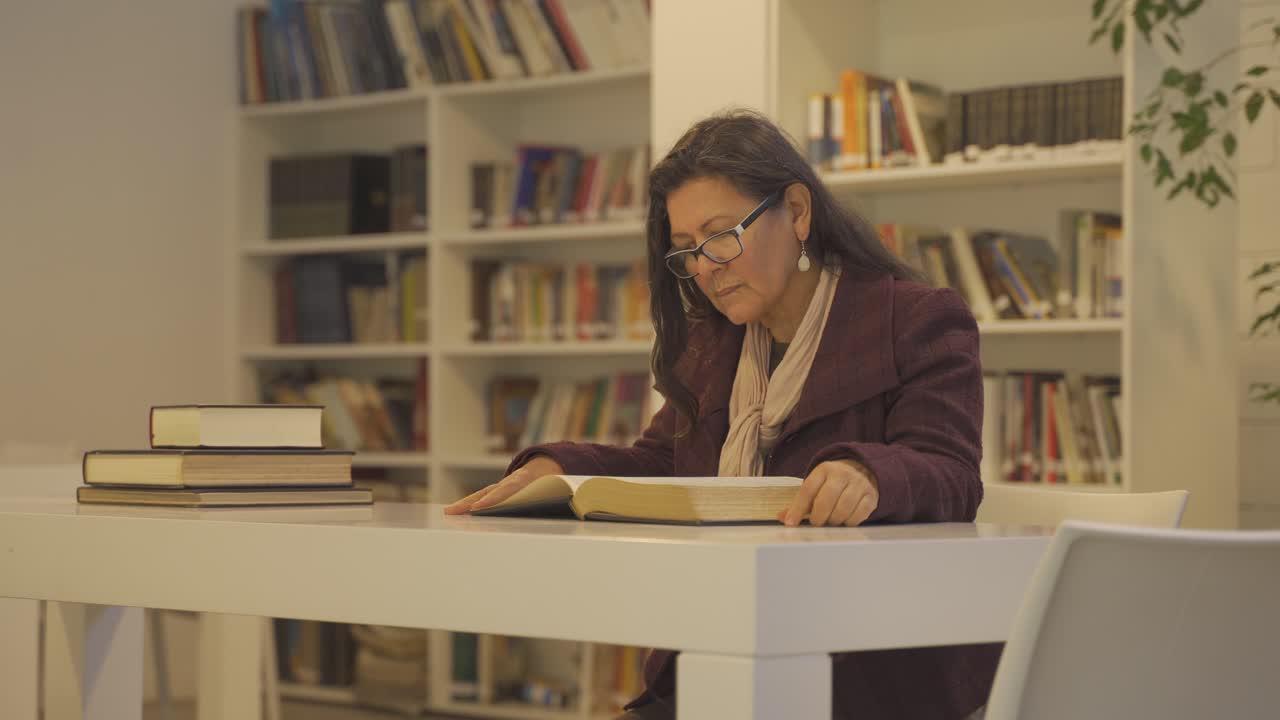 las mujeres de mediana edad están sentadas en el escritorio de una gran biblioteca reescribiendo el texto del libro