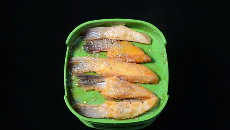 chuletas de pescado sin cocer en recipientes de plástico sazonados con semillas de sésamo - primer plano